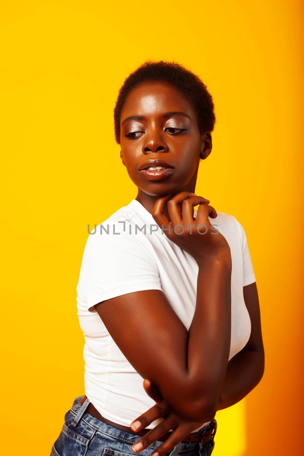 pretty young african american woman with curly hair posing cheerful gesturing on yellow background, lifestyle people concept close up