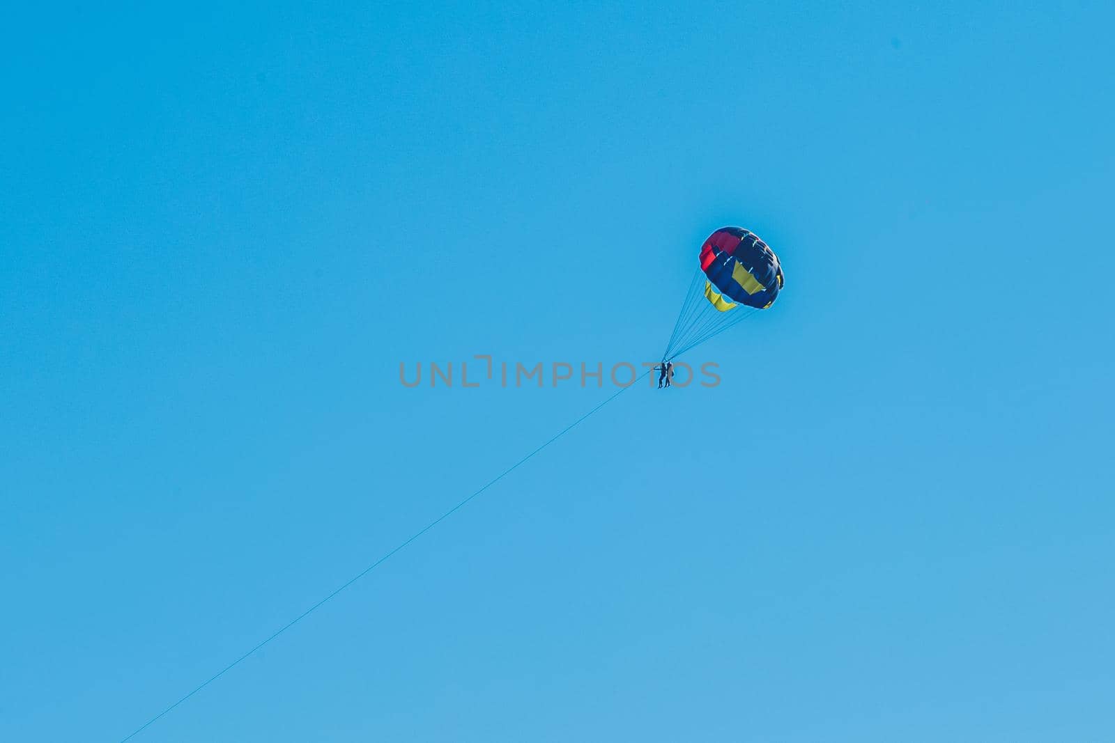 Extreme sports and exciting rest. Tourist fly on a parashute in the blue sky background.