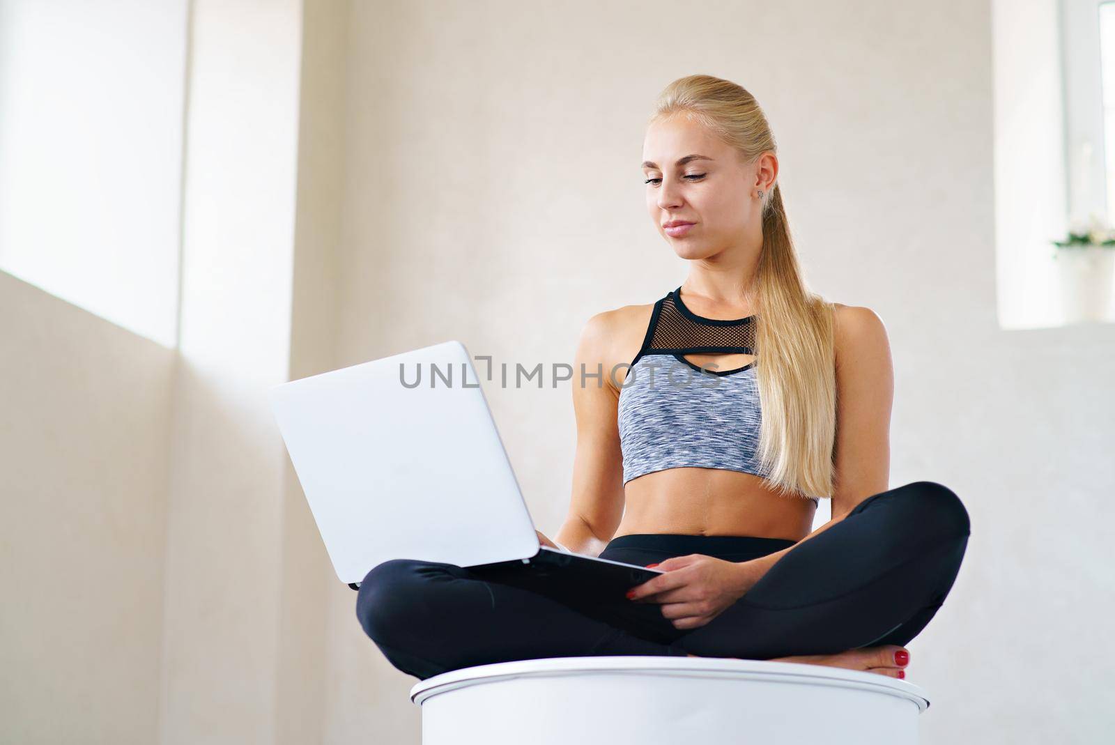 Sports business girl with laptop in lotus pose looks at laptop