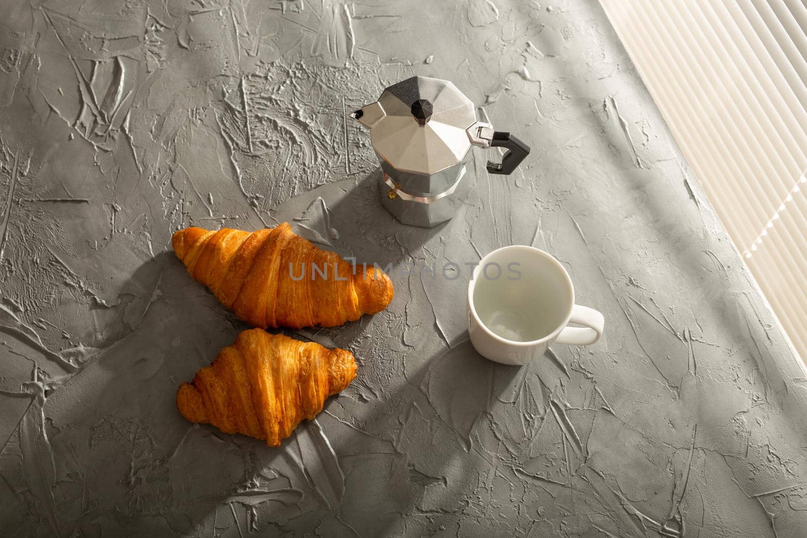 Breakfast with croissant on cutting board and black coffee. Morning meal and breakfast.