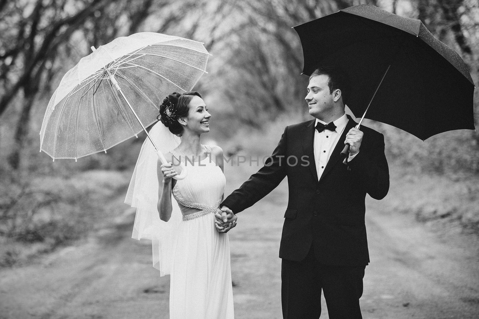 bride and groom on a rainy wedding day walking under an umbrella