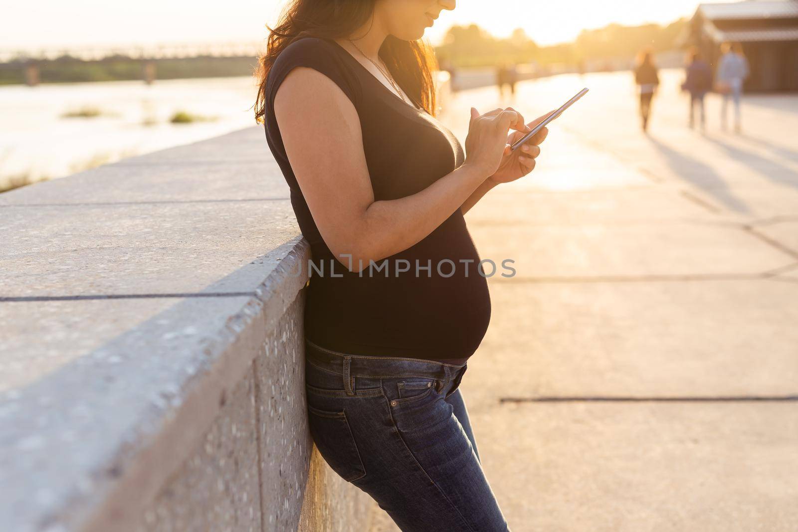 Close-up of pregnant woman with smartphone at park. Pregnancy, technology and communication concept. by Satura86
