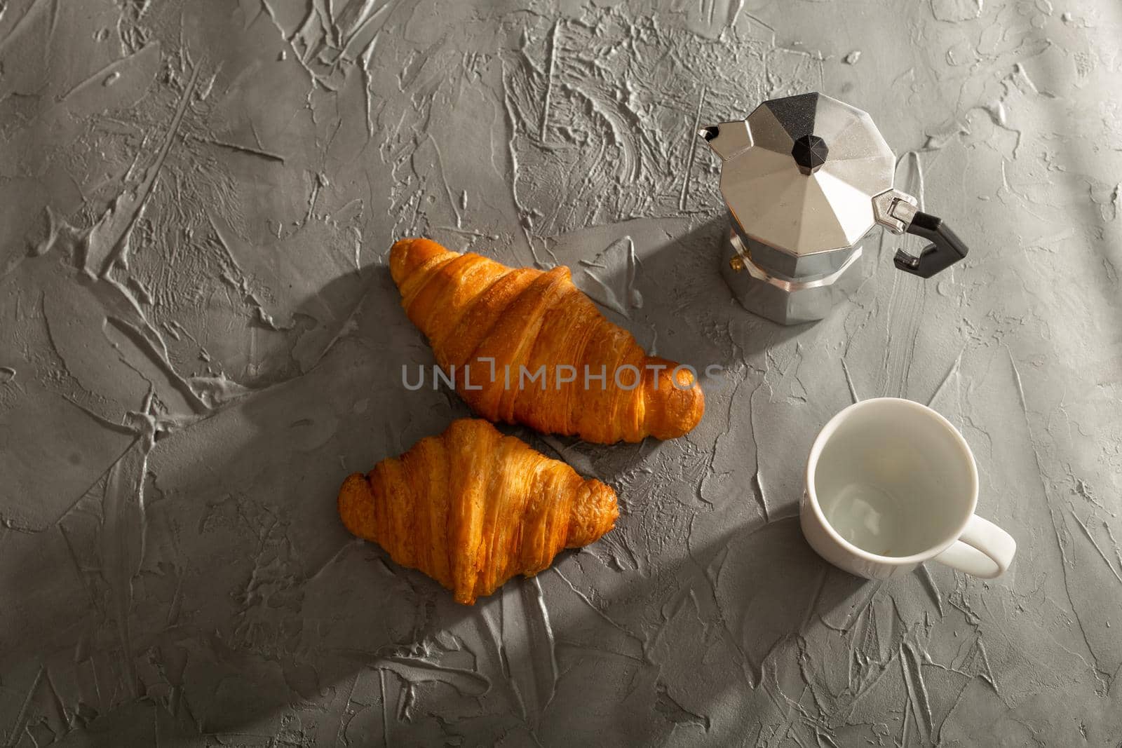 Breakfast with croissant on cutting board and black coffee. Morning meal and breakfast.