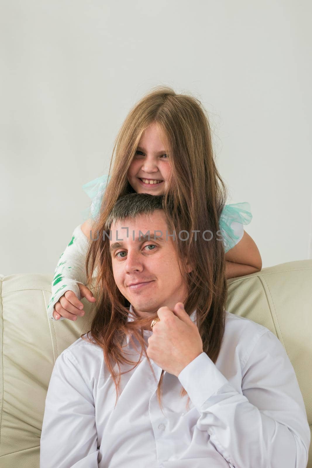 Father and his daughter having fun in their living room. Little girl have injury hand but she is happy be together her dad