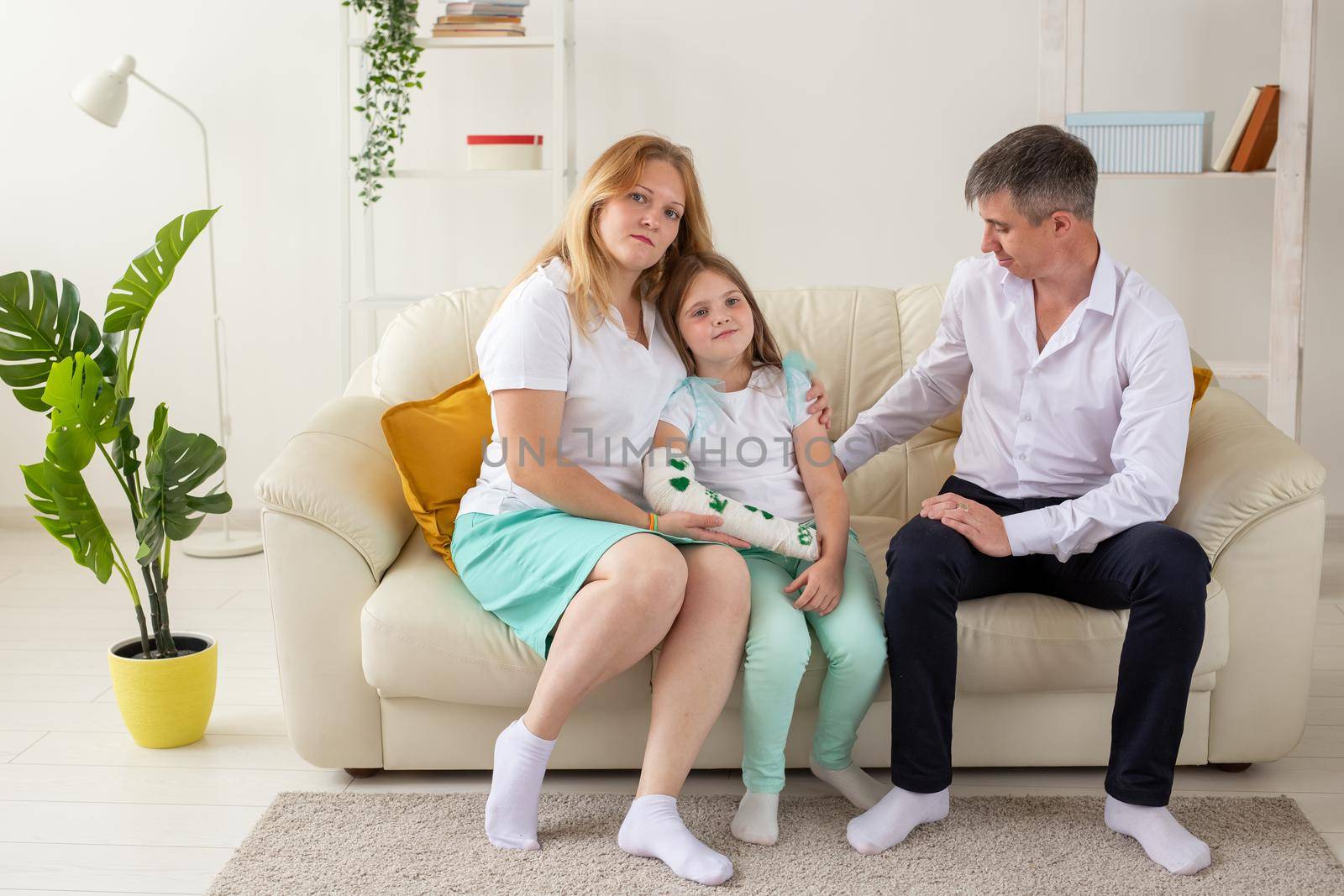 Family sitting on sofa in their living room. Daughter have injury hand but she is happy be together her family