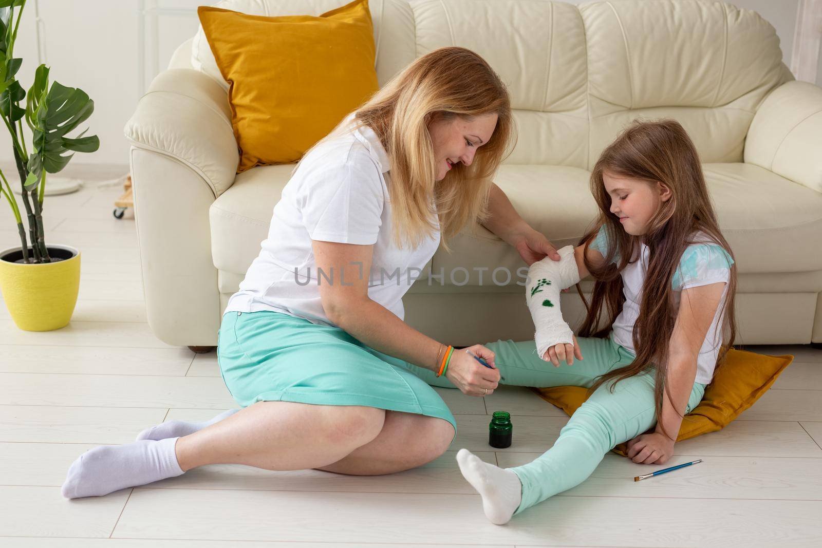 Mother and daughter drawing picture on bandage using paints. Play therapy concept