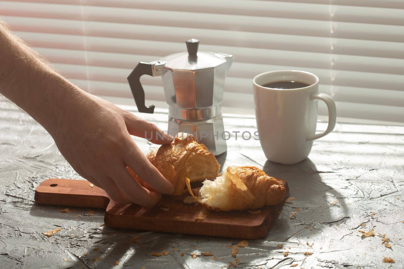 Breakfast with croissant on cutting board and black coffee. Morning meal and breakfast.