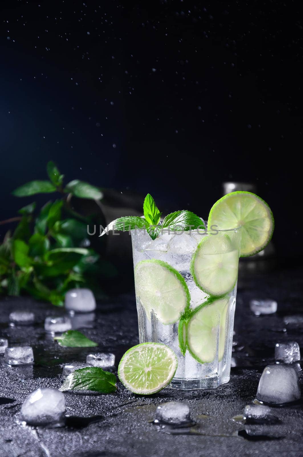 Cocktail Mojito or Lemonade with Lime, Mint and Ice on Dark Background. Concept Fresh Summer Drinks.