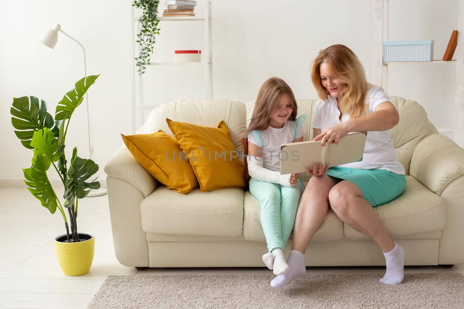 Child with broken arm and gypsum spend time at home with mother. Childhood illnesses, a positive outlook and recovery. by Satura86