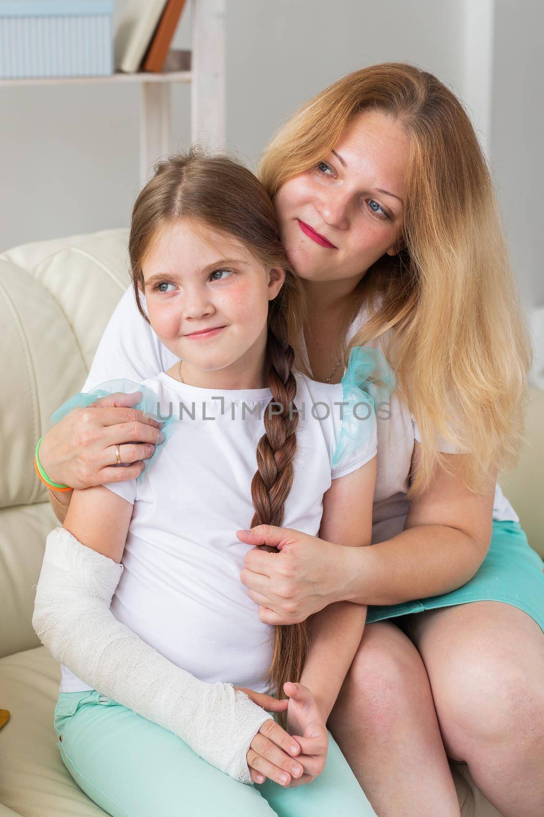 Mother hugs your child girl with a cast on a broken wrist or arm smiling. Childhood illnesses, a positive outlook and recovery. by Satura86