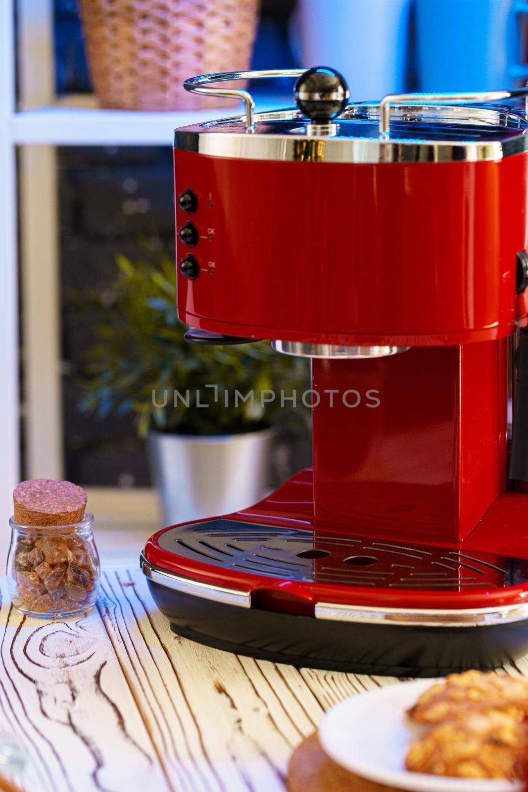 Red coffee machine on kitchen table with kitchen ware close up