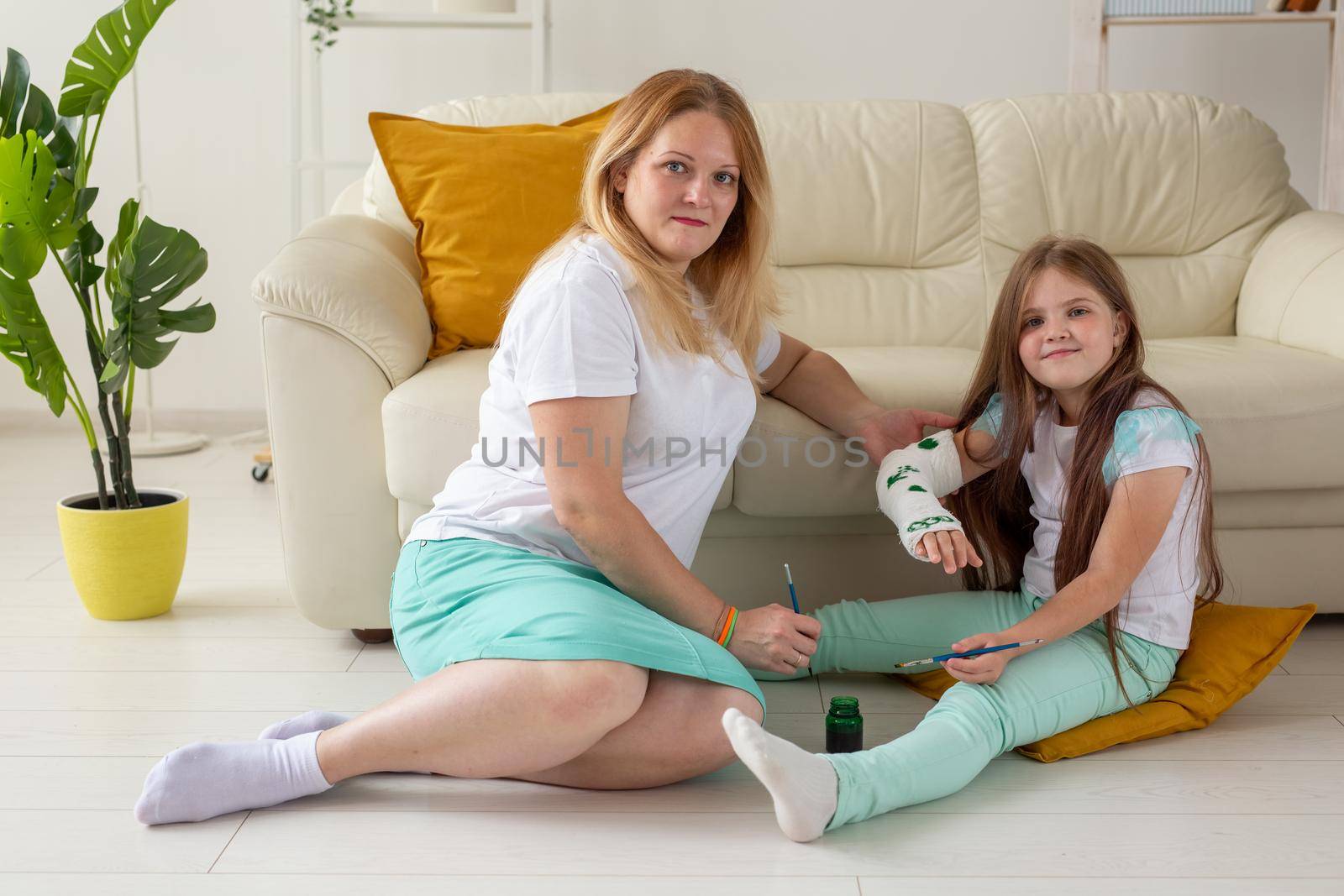 Mother and daughter drawing picture on bandage using paints. Play therapy concept