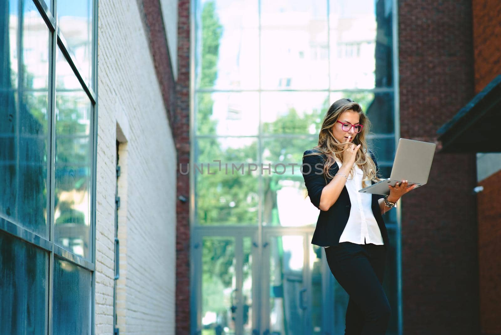 Business lady with a laptop is standing on the street