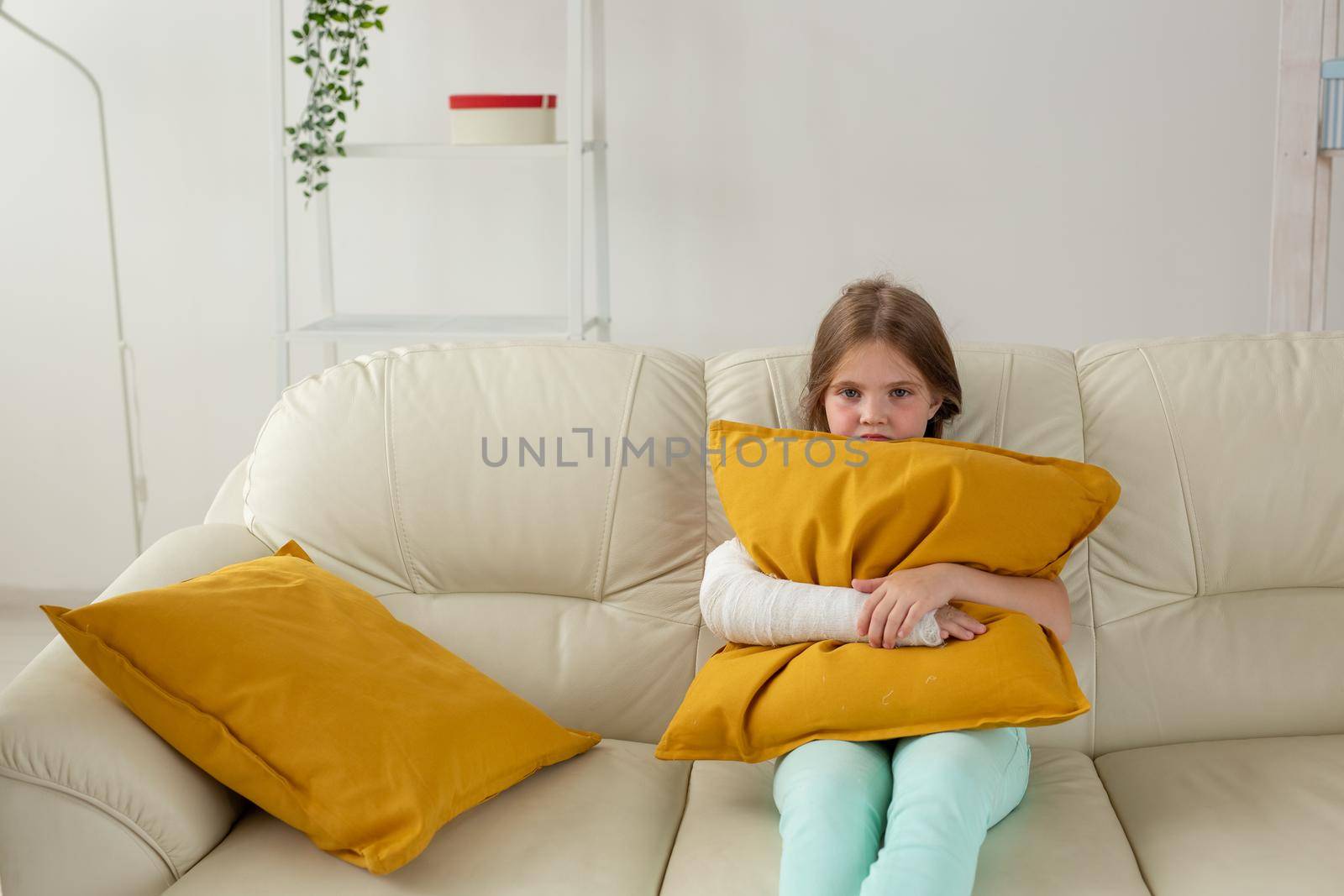 Child with a cast on a broken wrist or arm lying on a couch. Recovery and kid