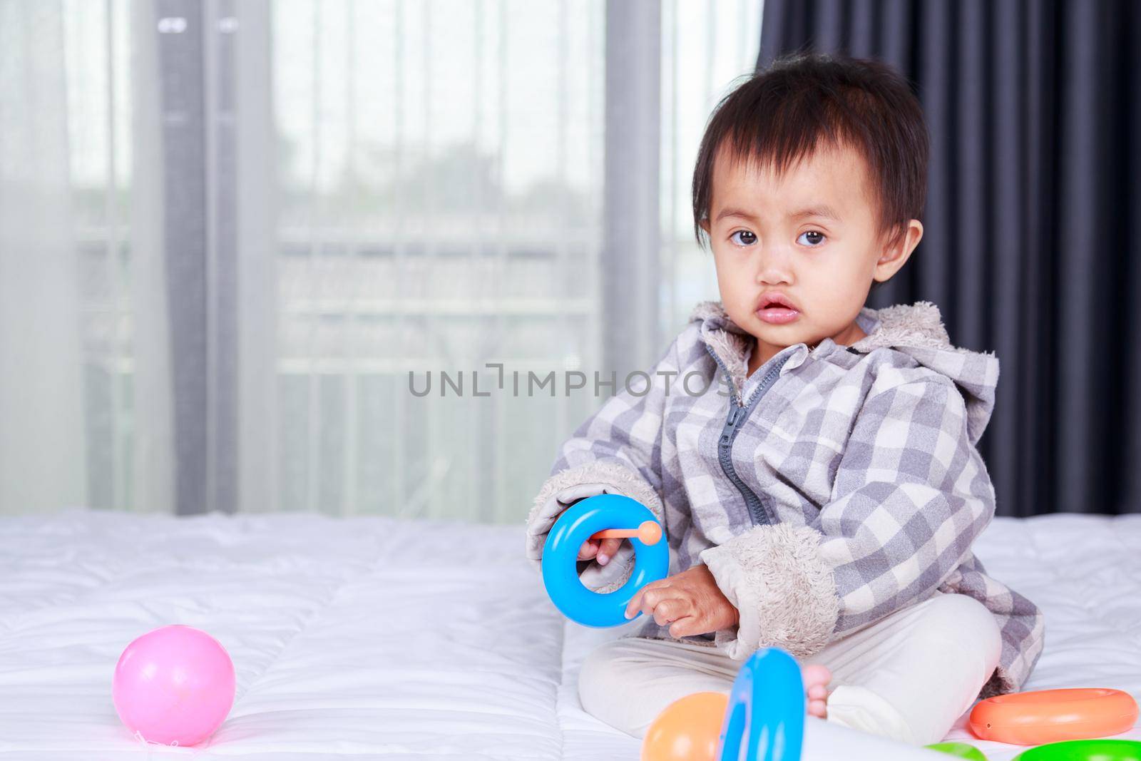 baby playing with toy on bed by geargodz