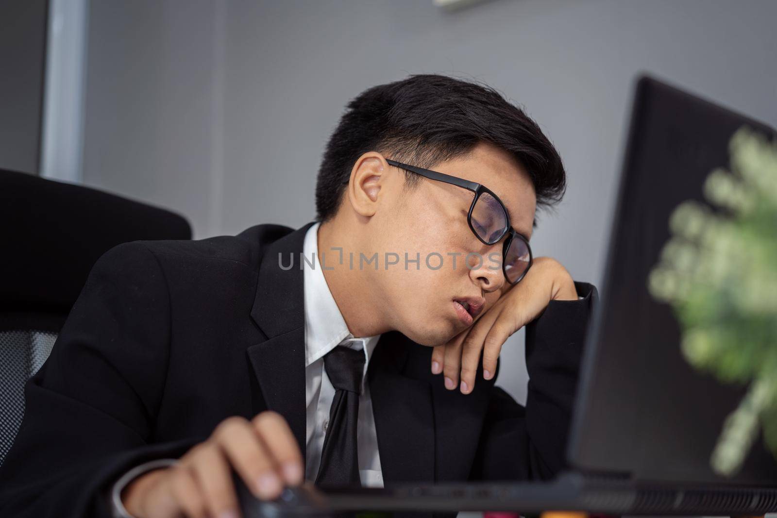 business man sleepy on working desk between using laptop computer by geargodz