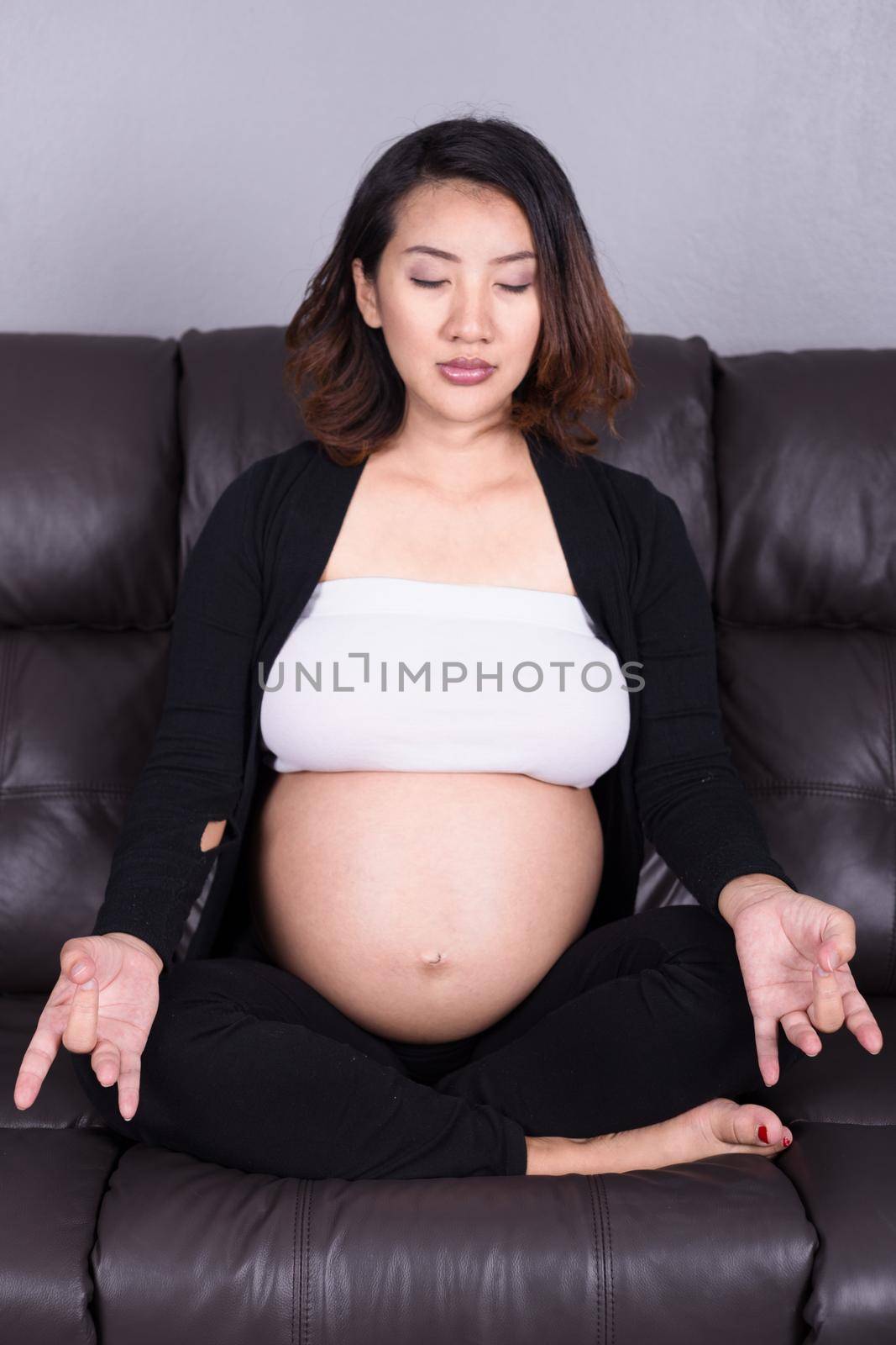 pregnant woman practicing yoga on sofa