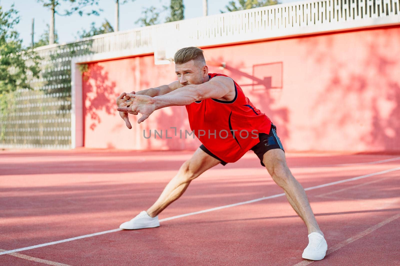 sports man in a red t-shirt on the sports ground doing exercises. High quality photo