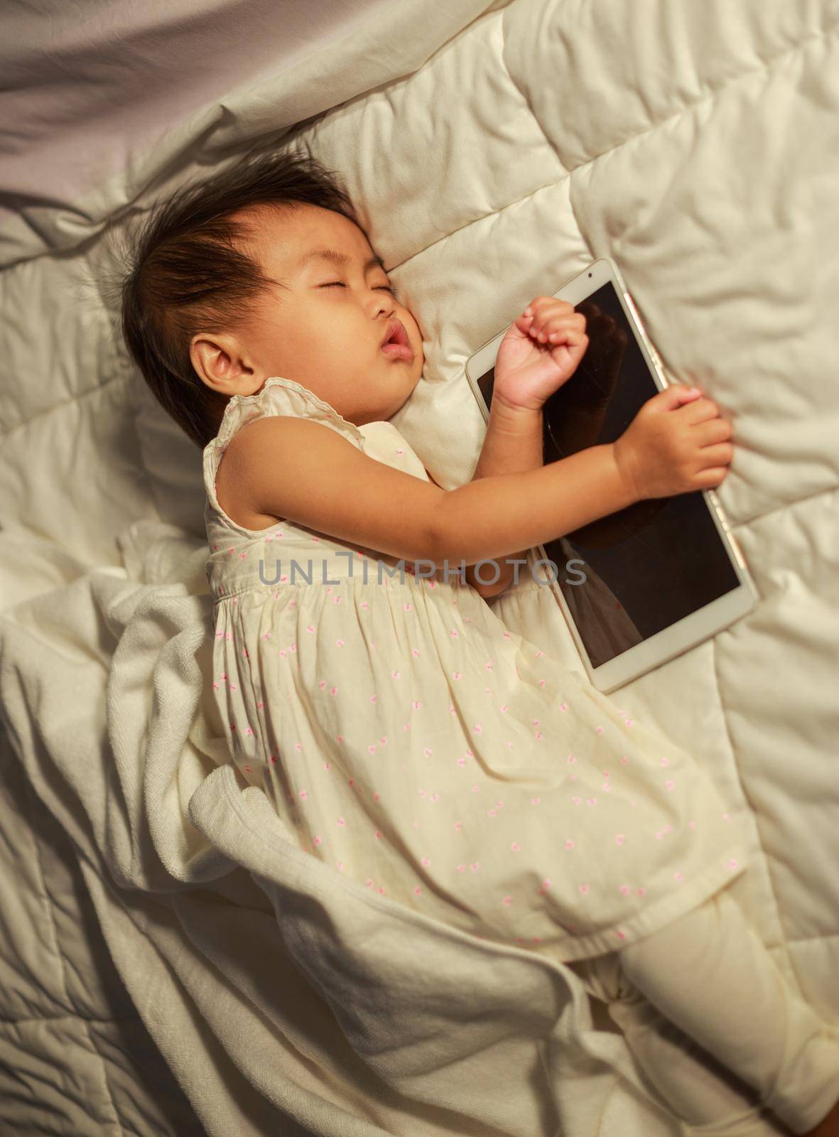 baby sleeping on bed after playing tablet by geargodz