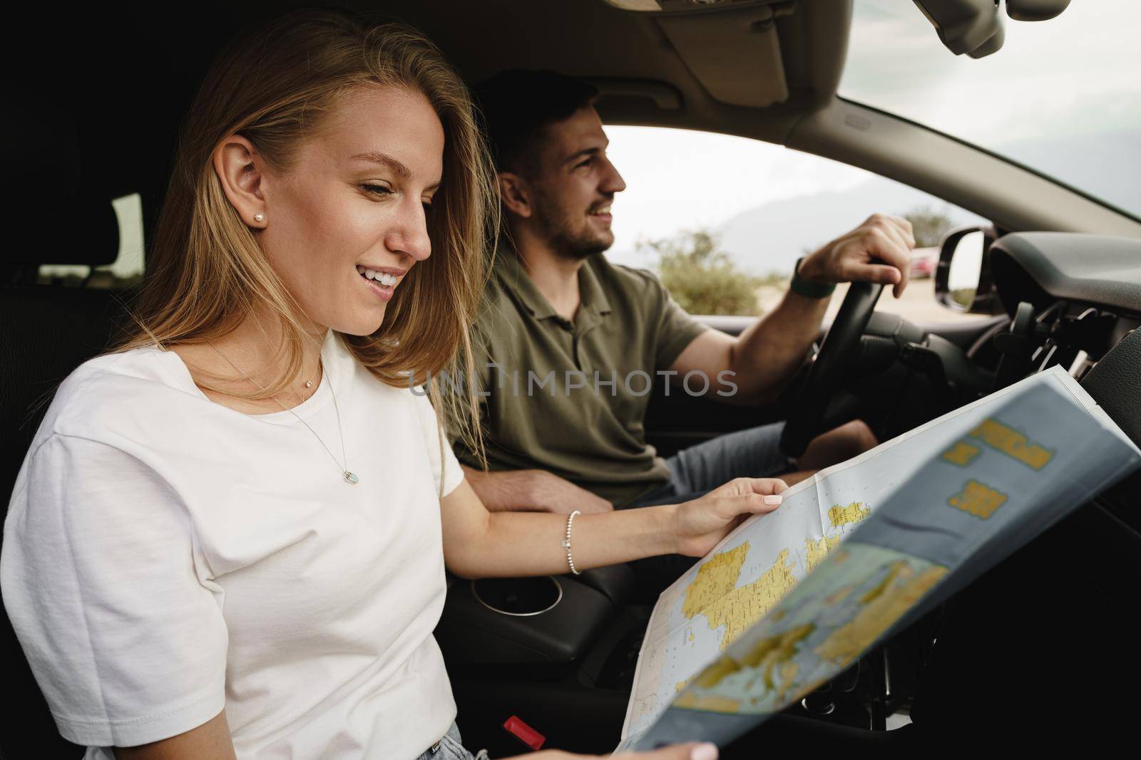 Young loving couple on a road trip using map inside a car, close up