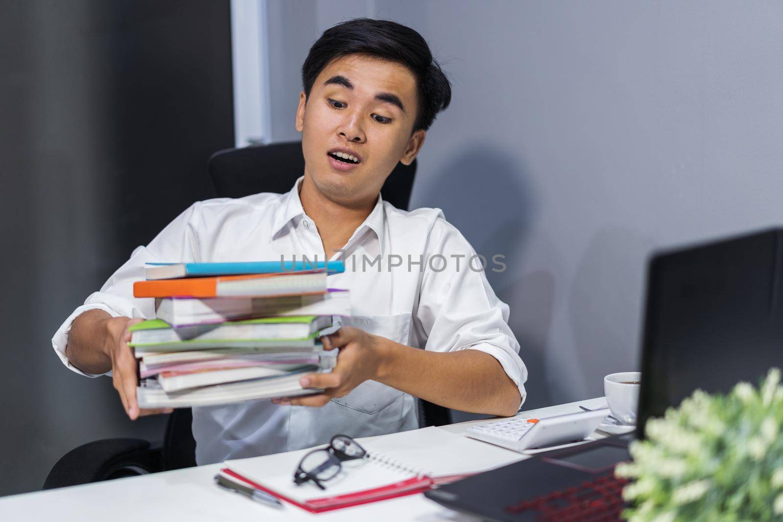 tired student sitting at the table with book and laptop