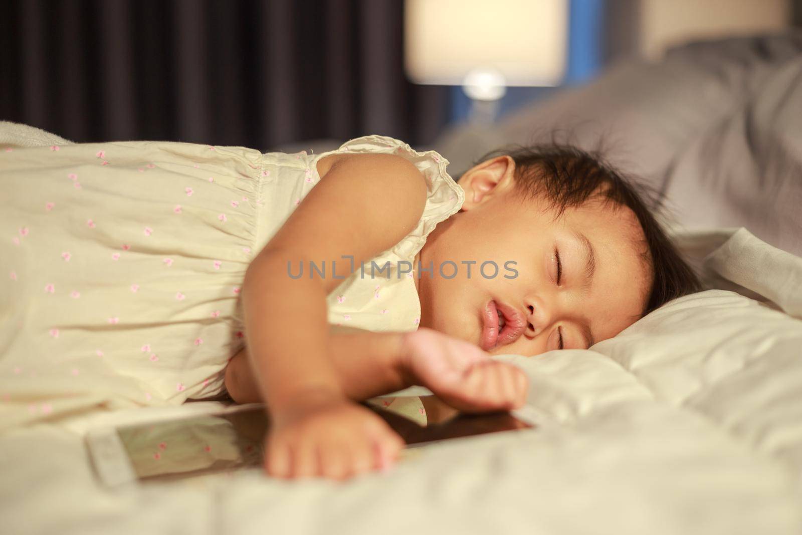 baby sleeping on bed after playing digital tablet