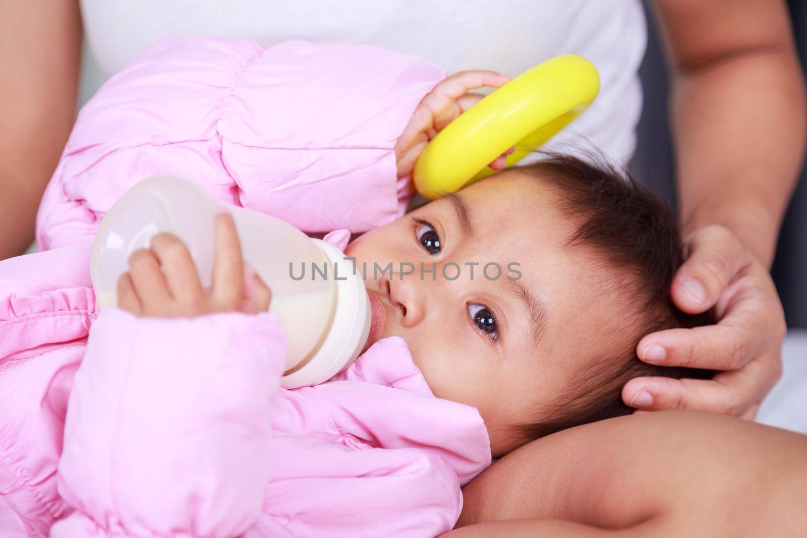 baby drinking a milk from bottle with mother on a bed