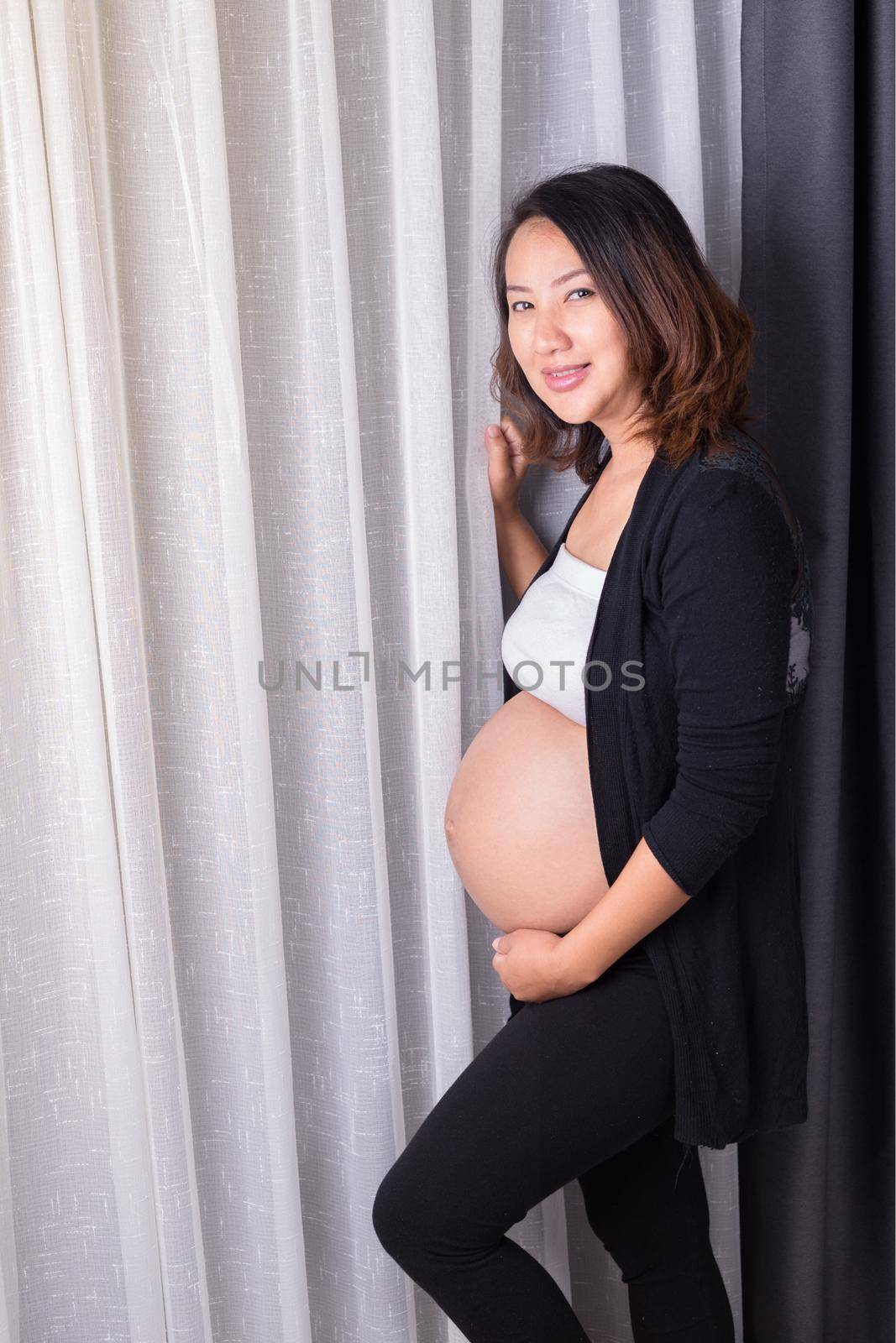 Pregnant woman standing near window in room