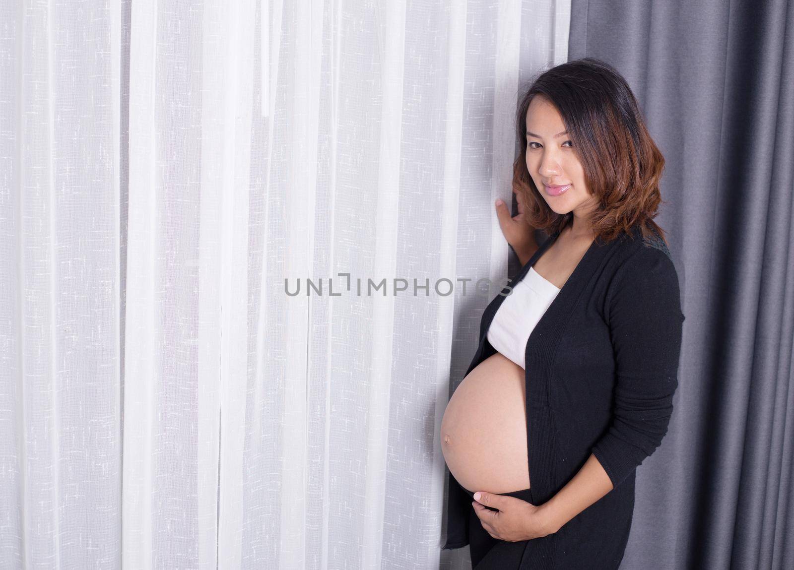 Pregnant woman standing near window in room