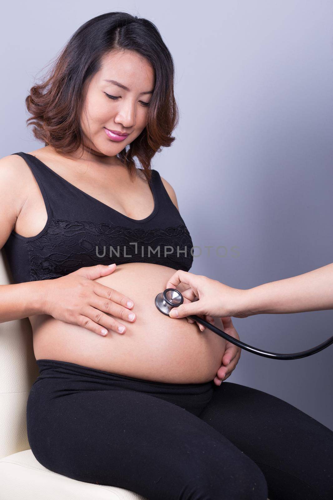 Belly of a pregnant woman examined with a stethoscope