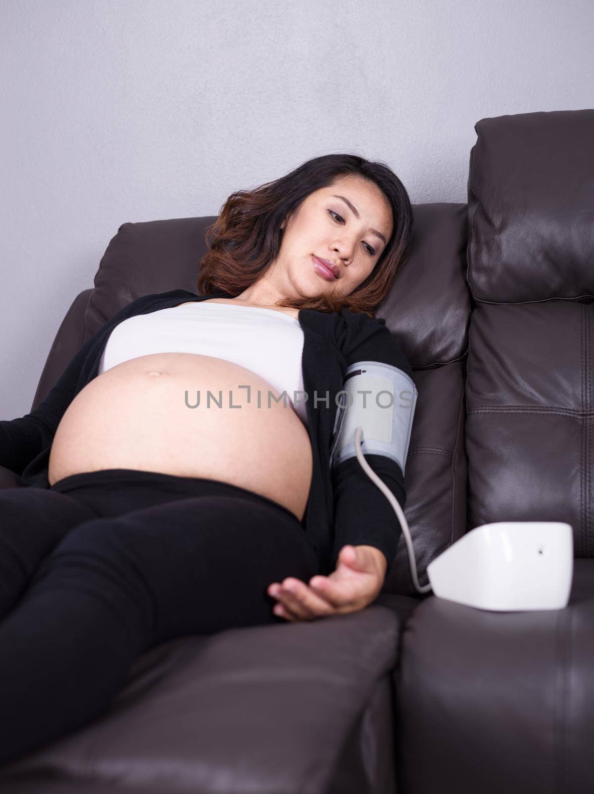 Pregnant woman measures blood pressure with automatic sphygmomanometer