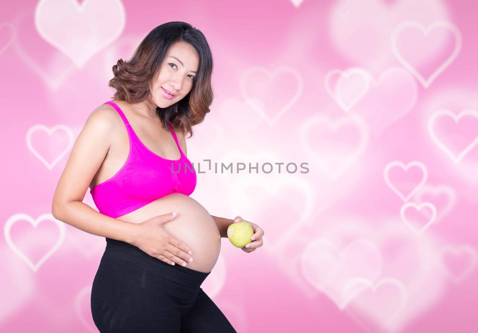 Beautiful pregnant woman with green apple on heart background