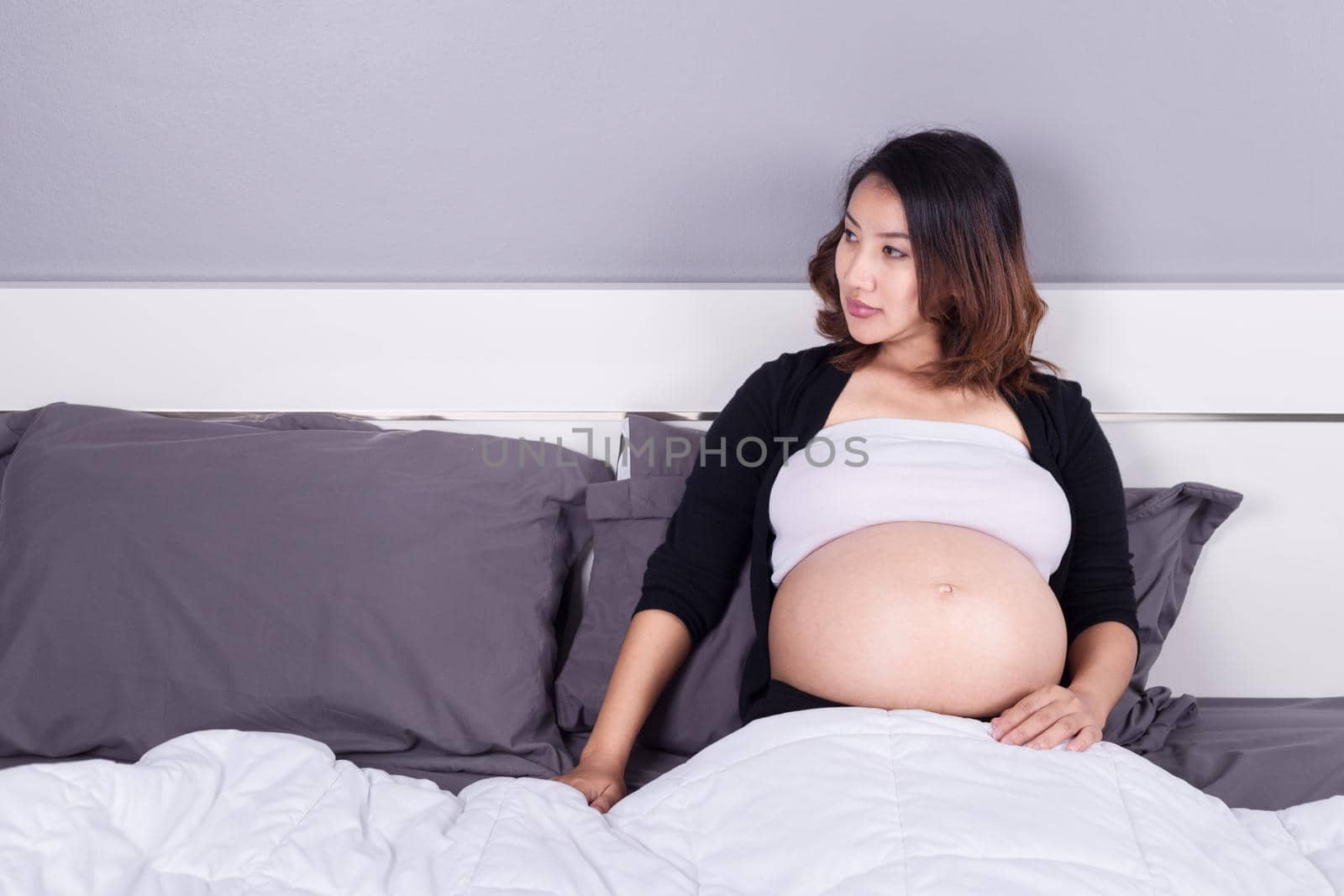 pregnant woman lying on bed in the bedroom by geargodz