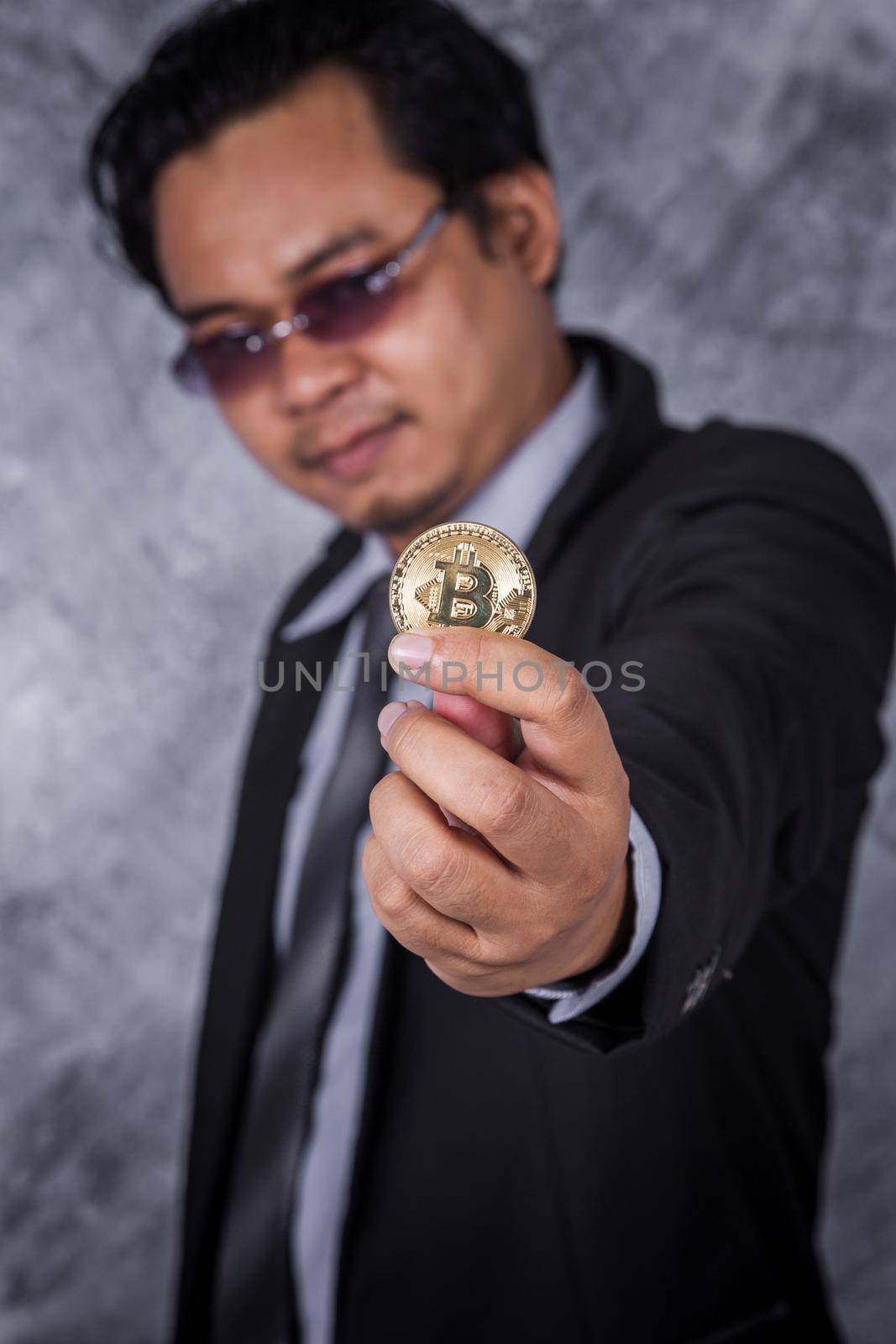man holding golden bitcoin in hand by geargodz
