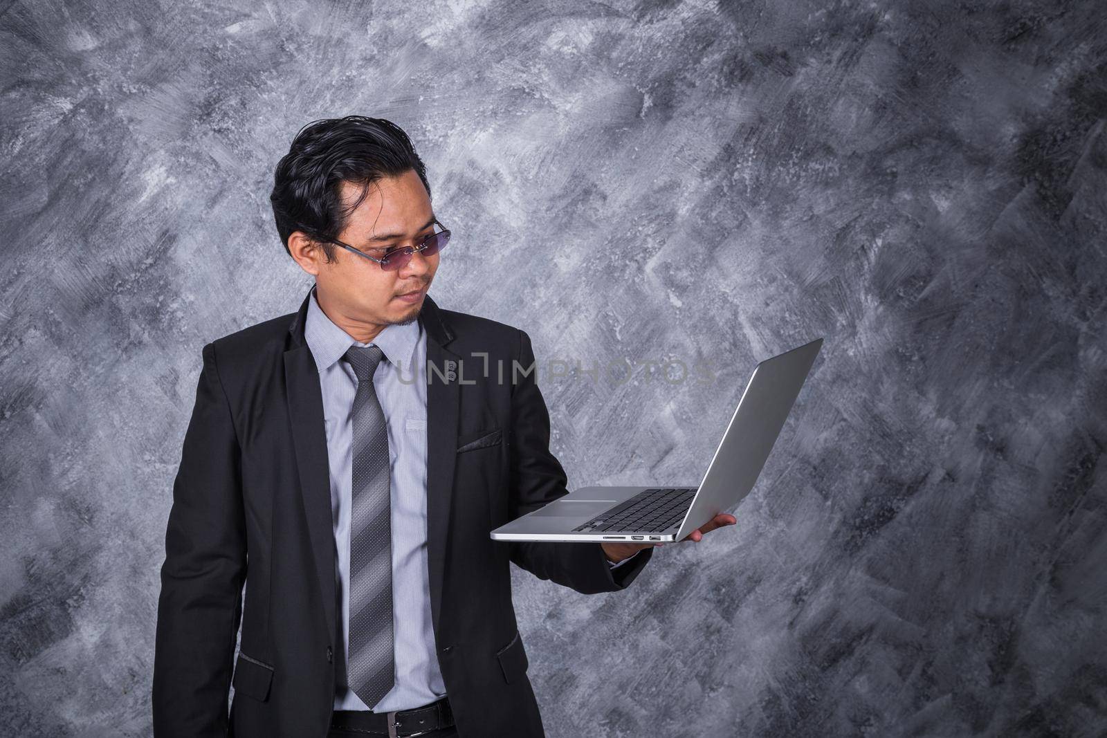young business man holding laptop with wall background