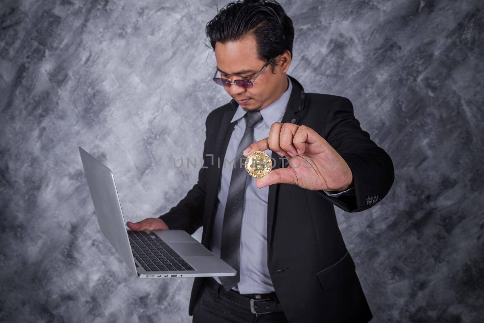 business man holding golden bitcoin with laptop computer  by geargodz
