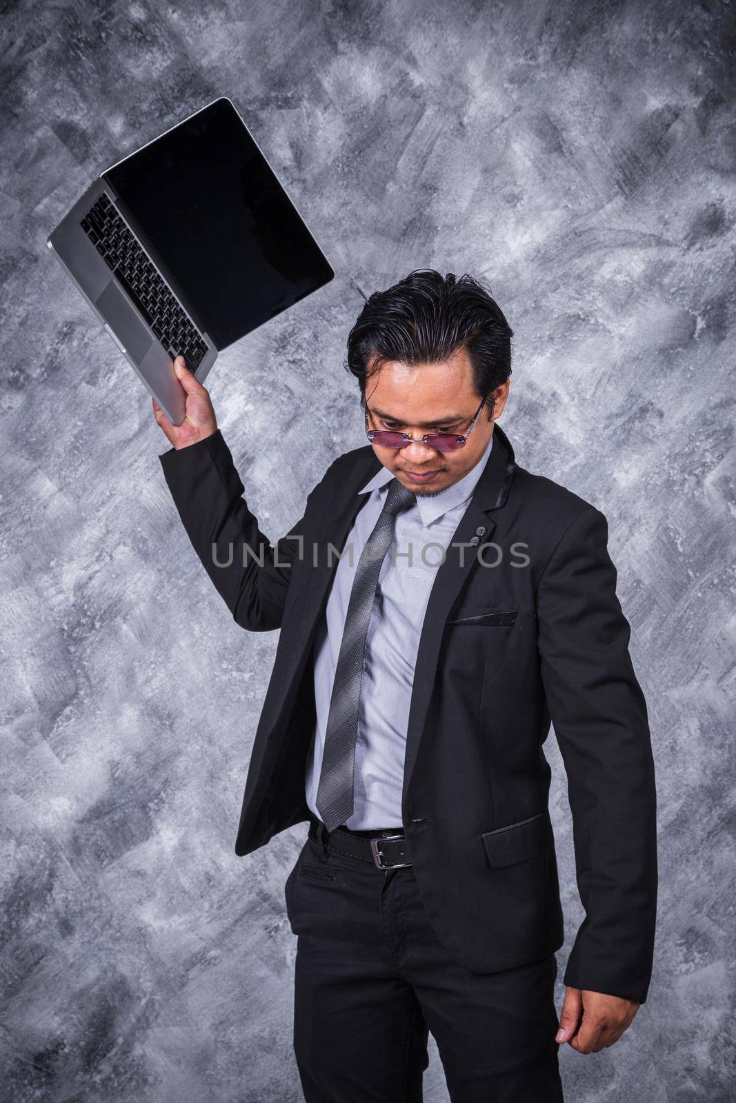 very angry business man is throwing away his laptop