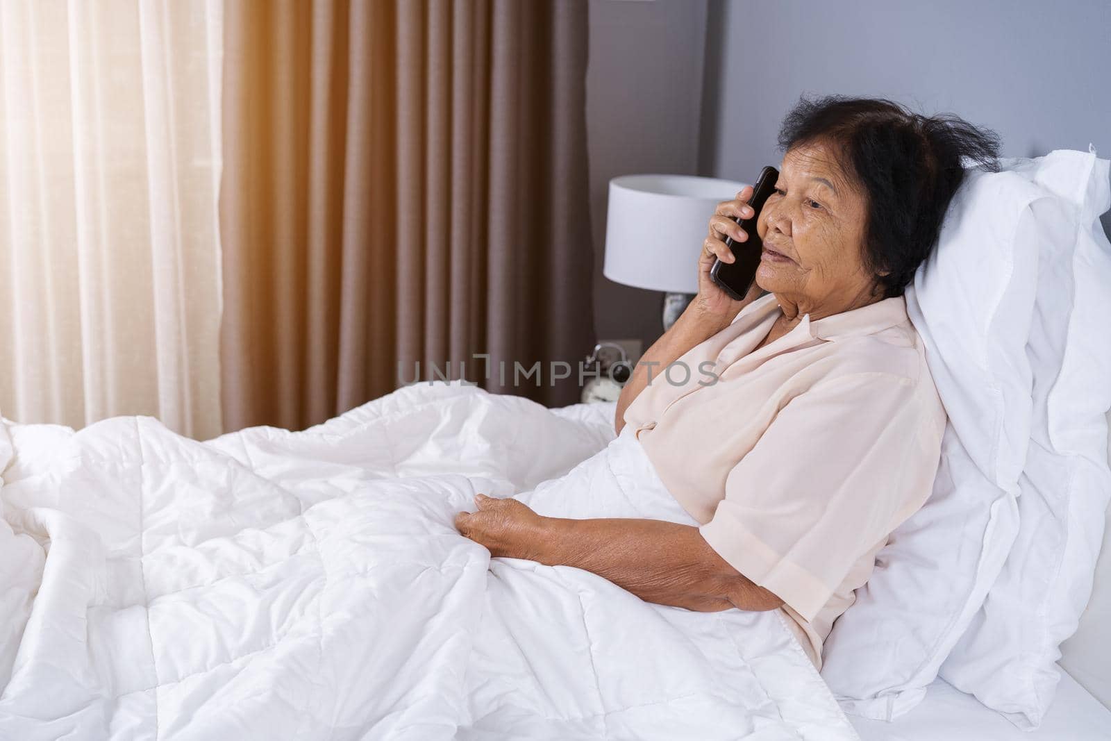 senior woman talking on mobile phone in a bed