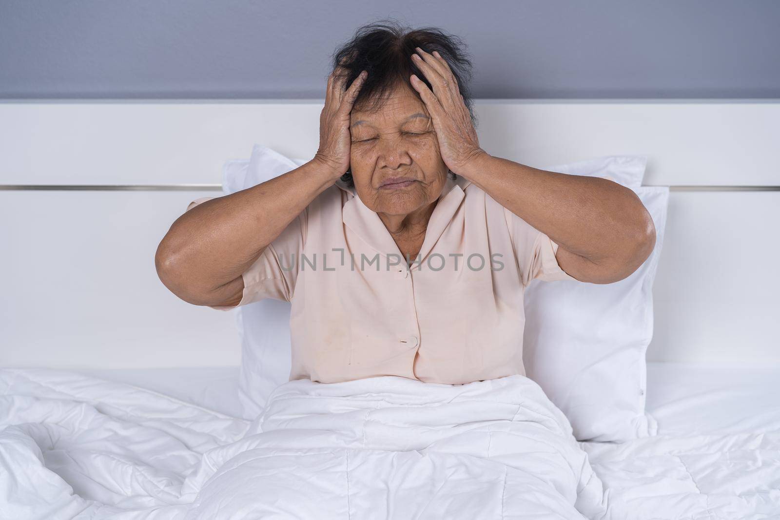 Senior woman got a headache on a bed