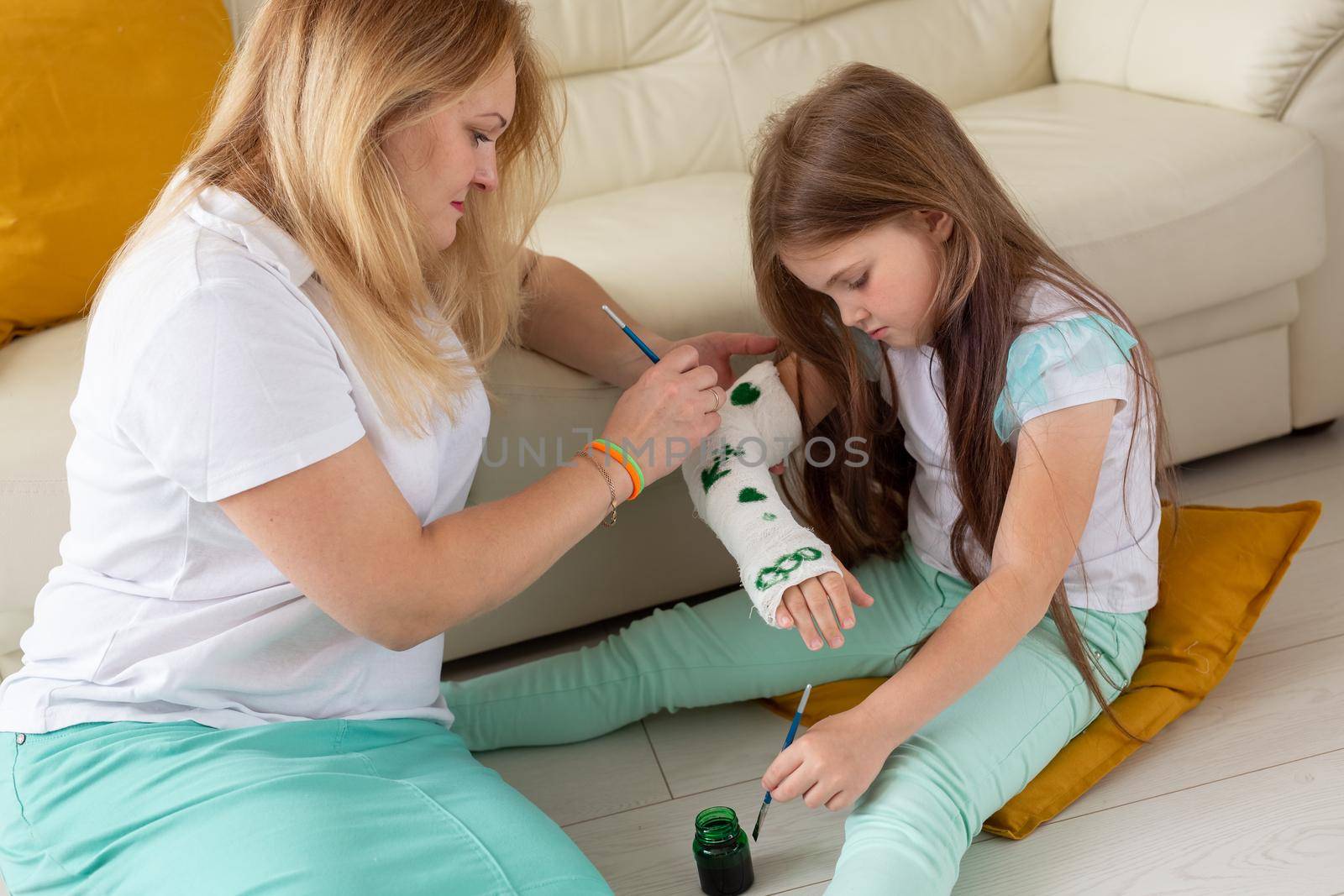 Mother and daughter drawing picture on bandage using paints. Play therapy concept. by Satura86