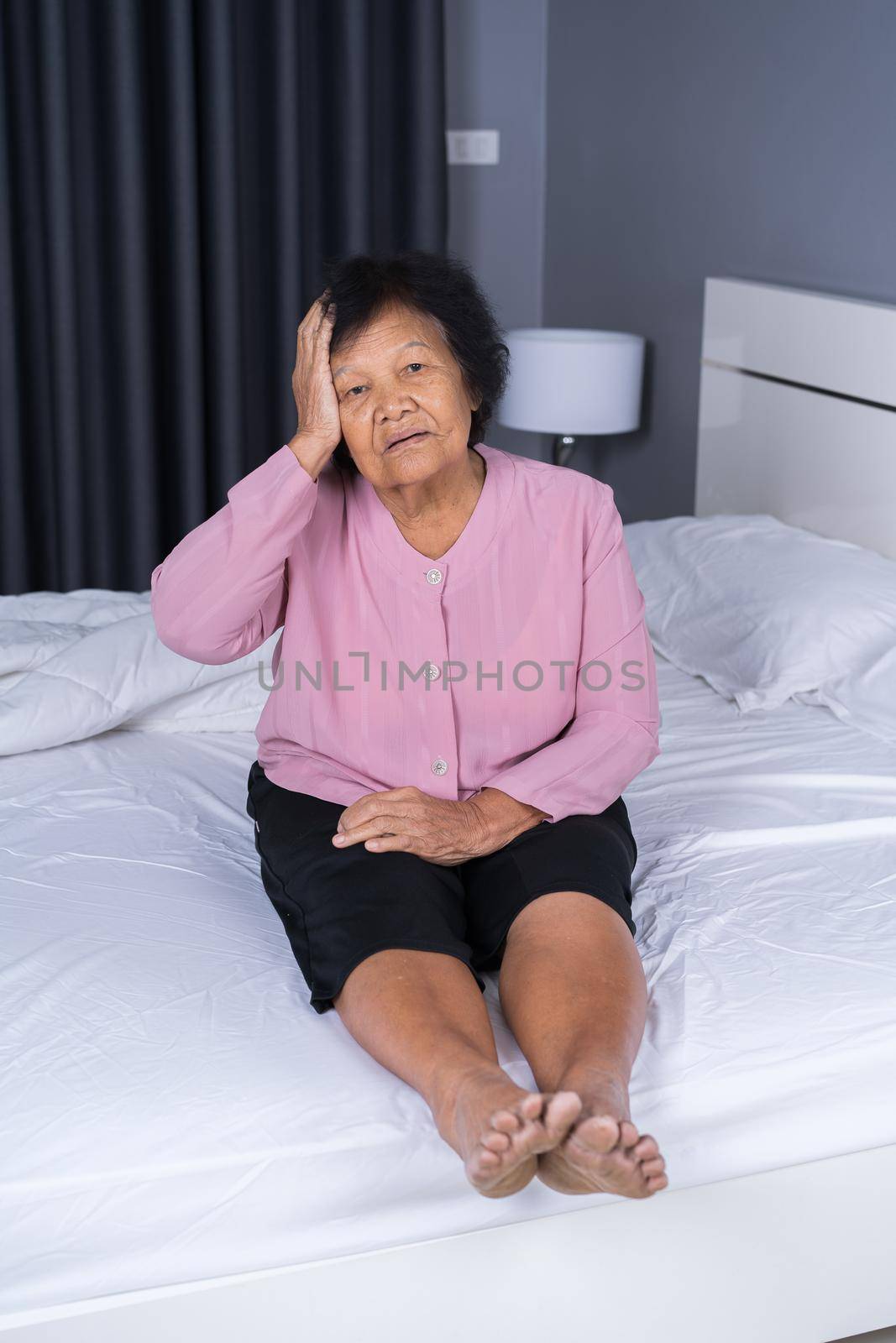Senior woman got a headache on a bed