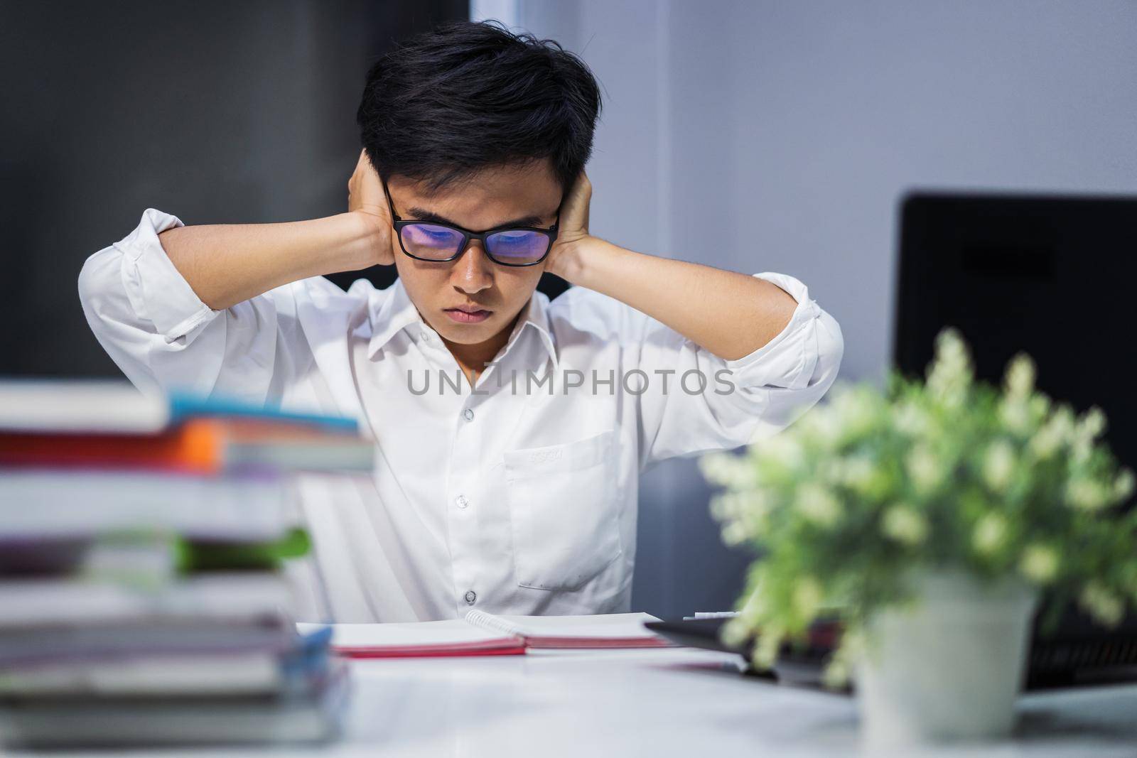 student reading a book and closing ears with both hands, stressed by noise