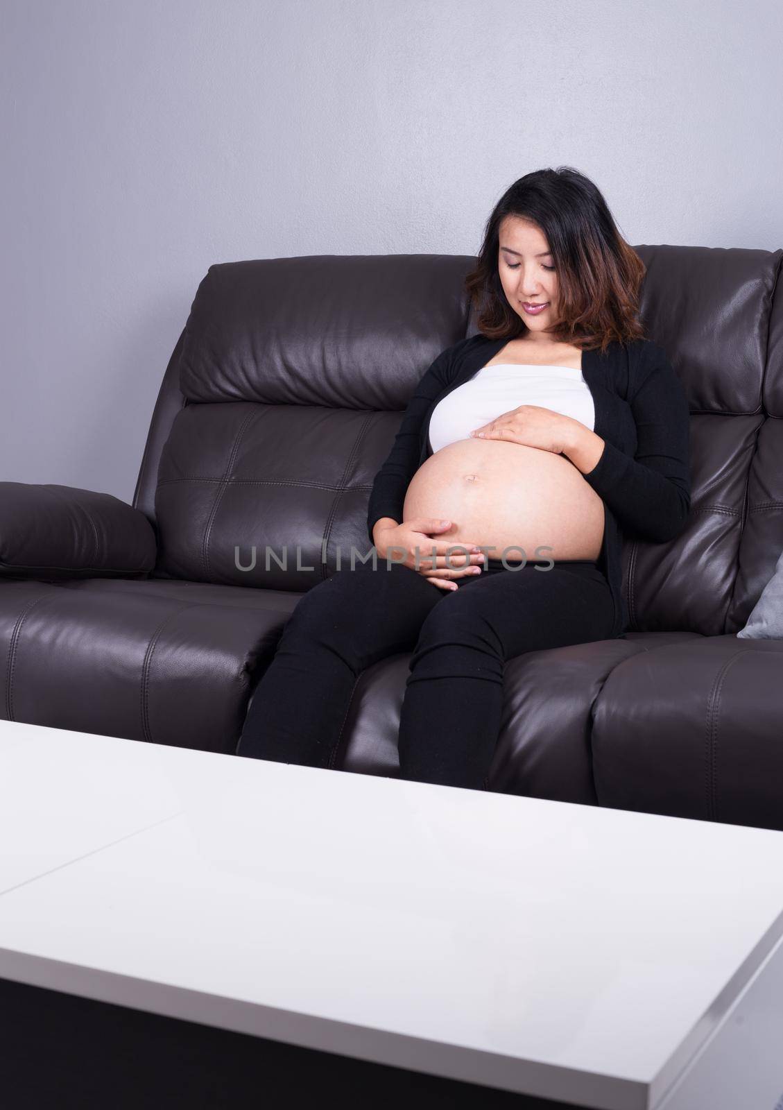 pregnant woman resting at home on sofa by geargodz