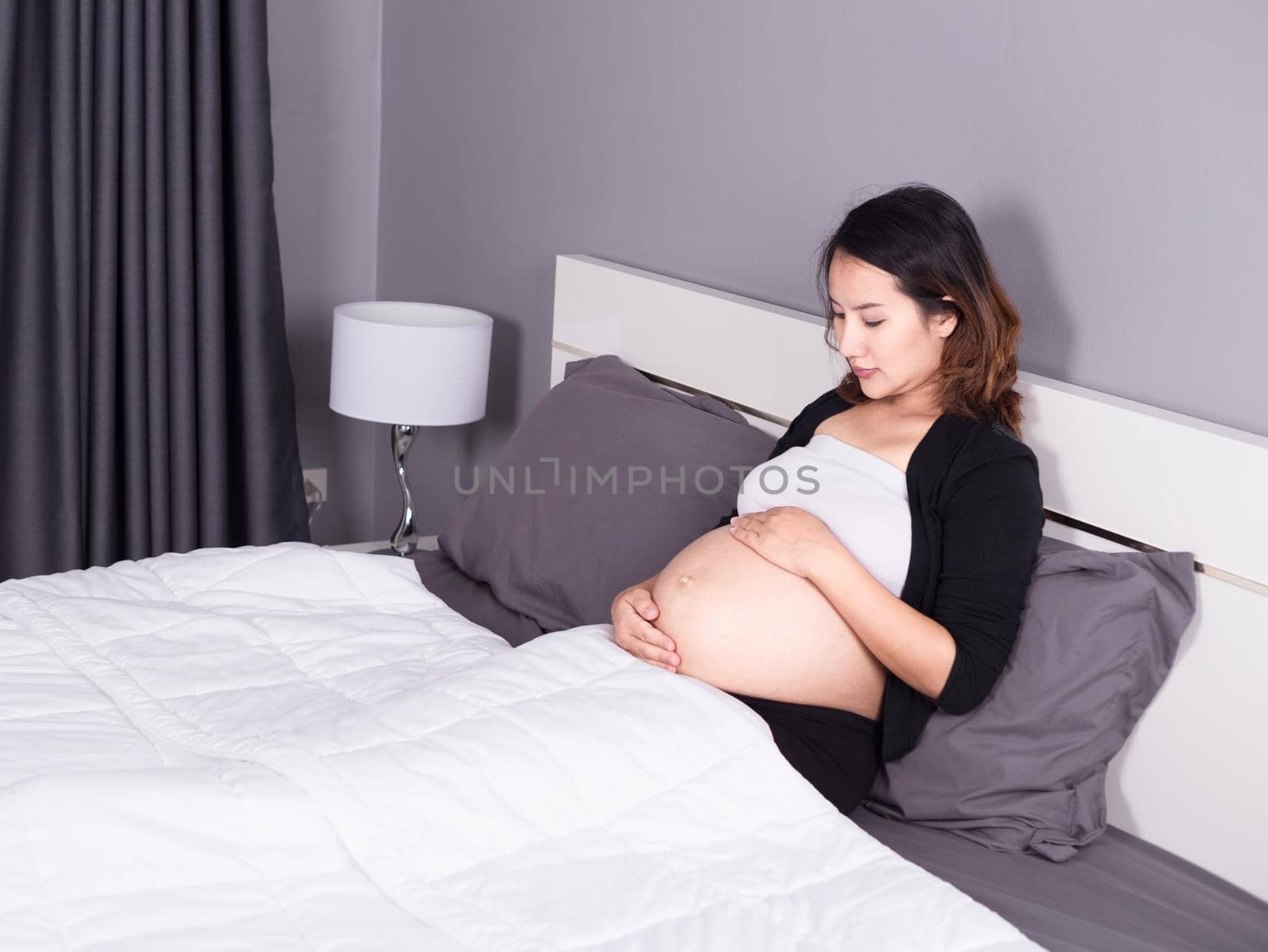 pregnant woman looking at her belly while lying on the bed