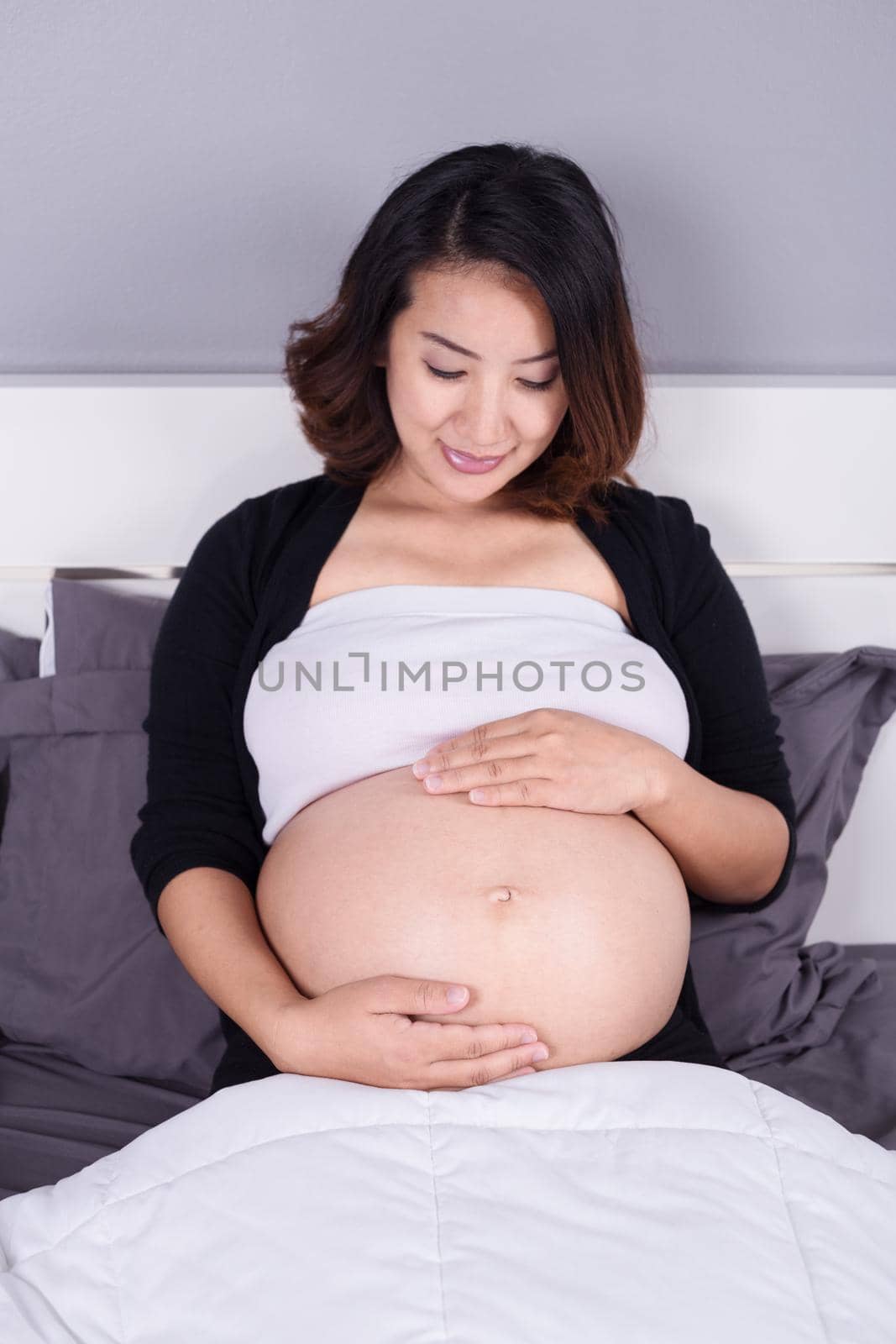 pregnant woman looking at her belly while lying on the bed