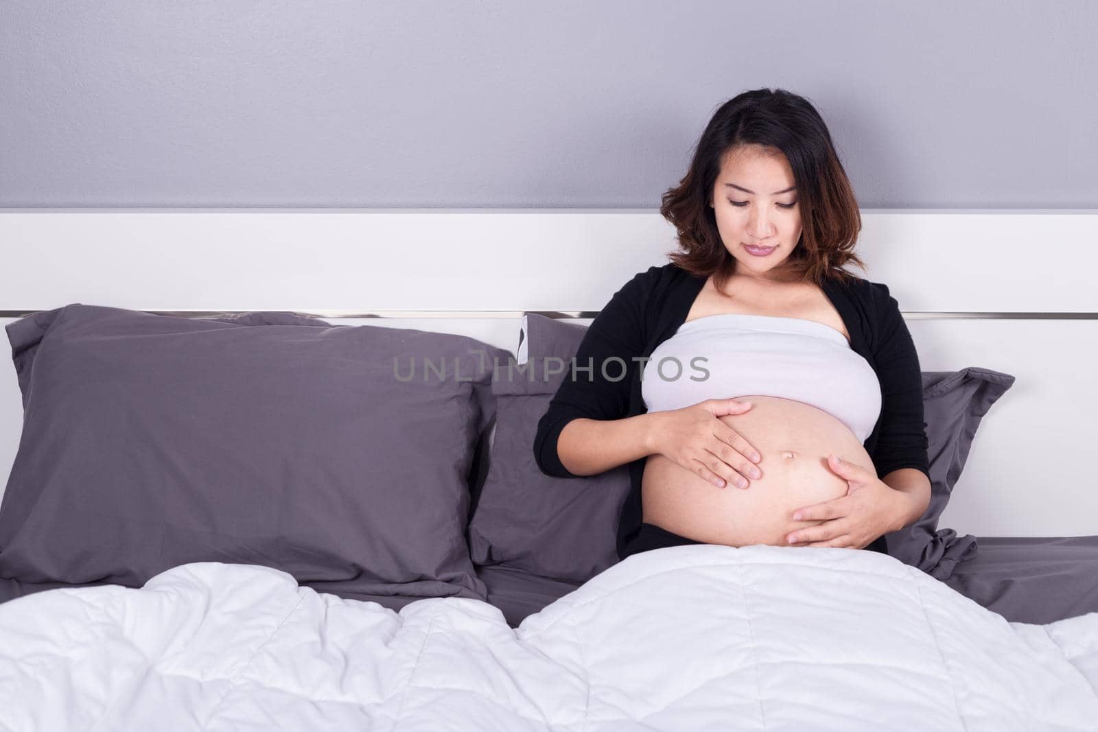 pregnant woman looking at her belly while lying on the bed