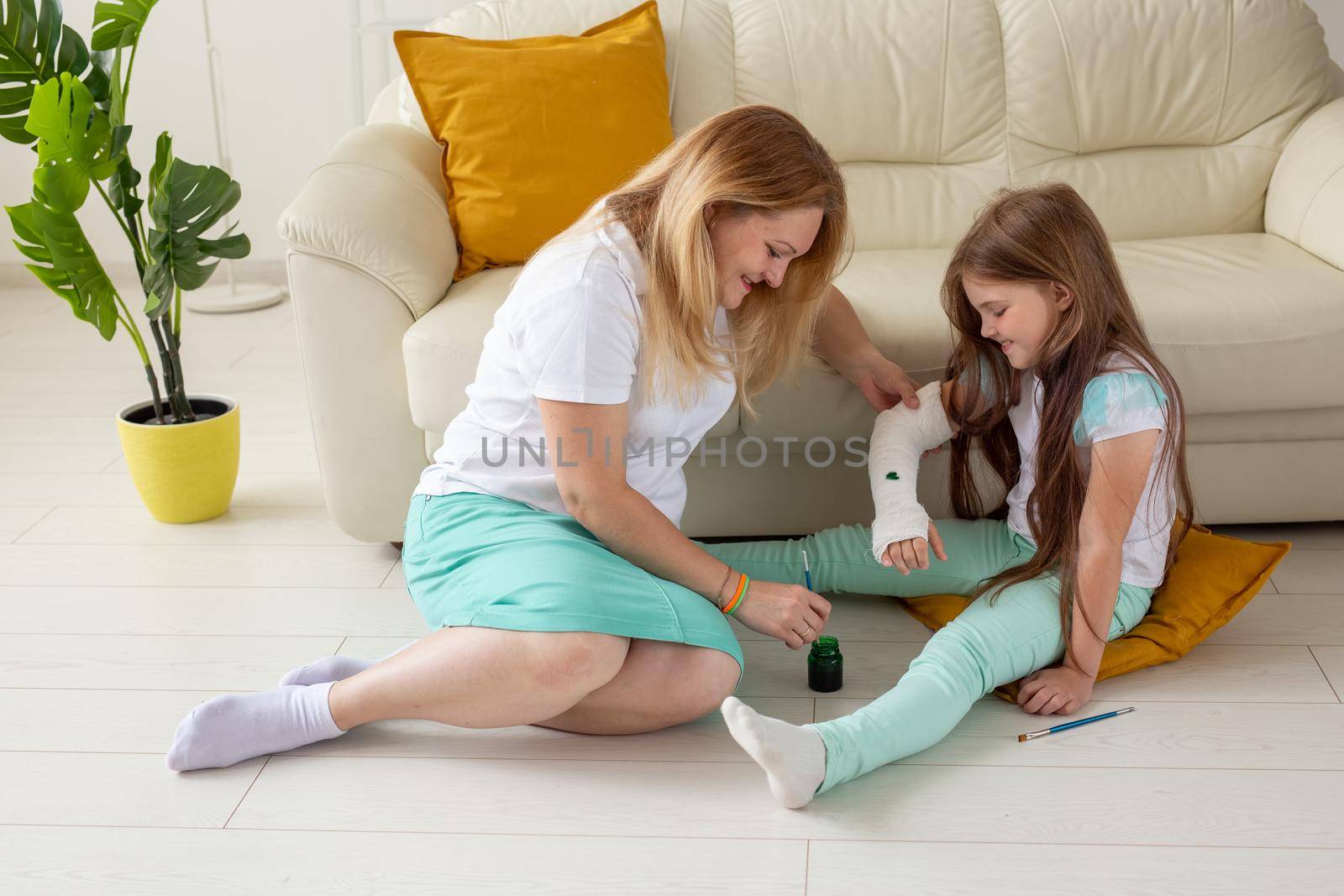 Mother and daughter drawing picture on bandage using paints. Play therapy concept. by Satura86