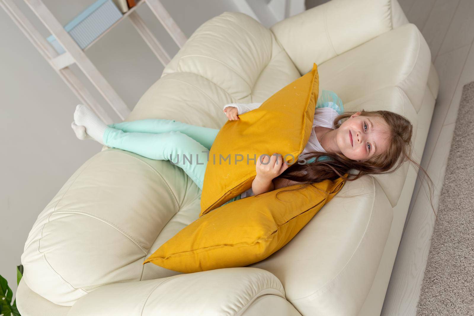 Child with a cast on a broken wrist or arm smiling and having fun on a couch. Positive attitude, recovery and kid.