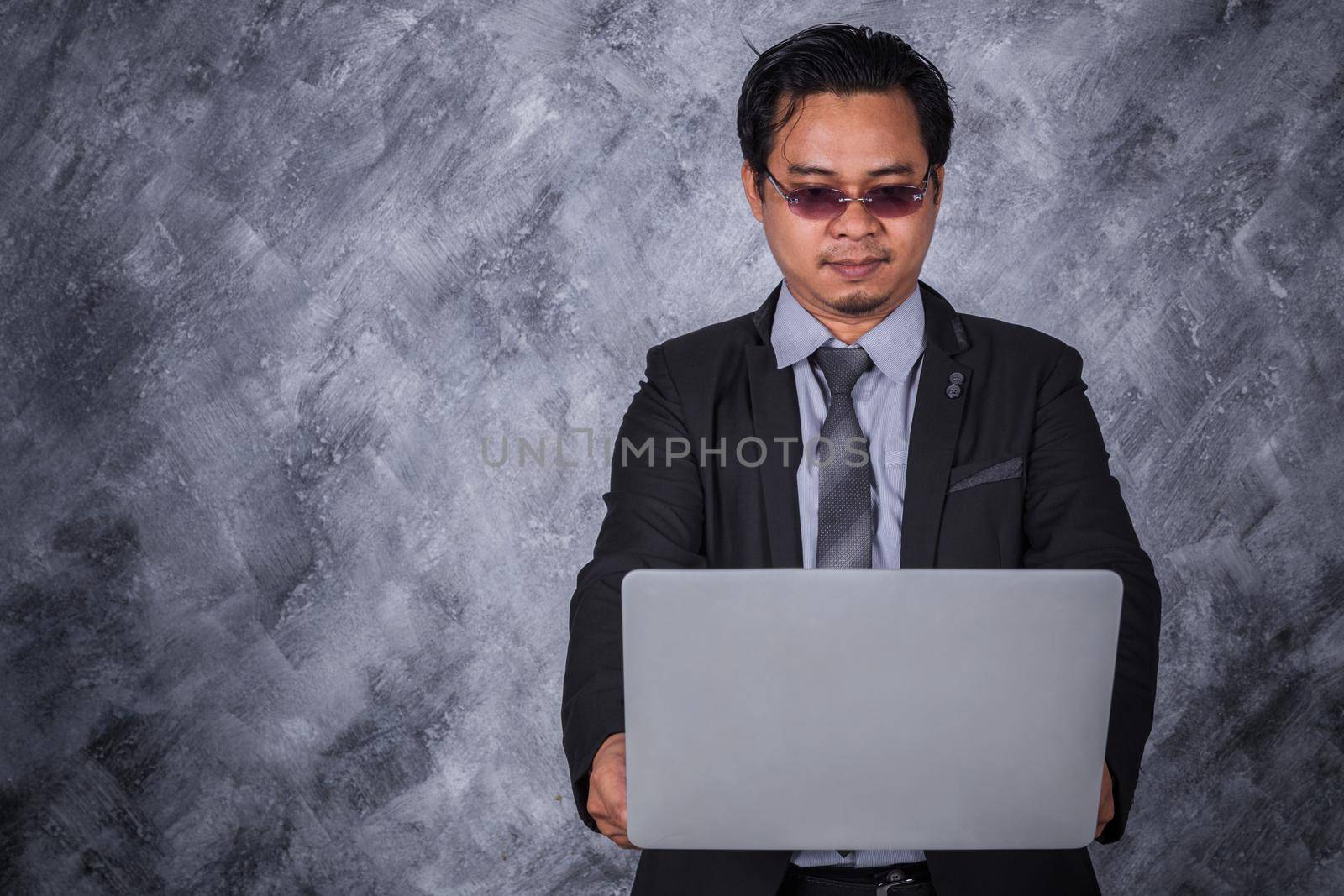 young business man holding laptop with wall background