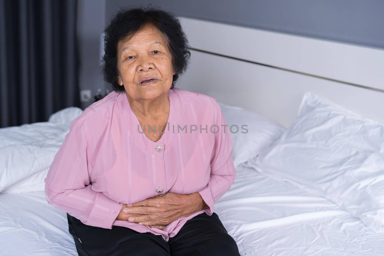 senior woman suffering from stomachache on bed at home